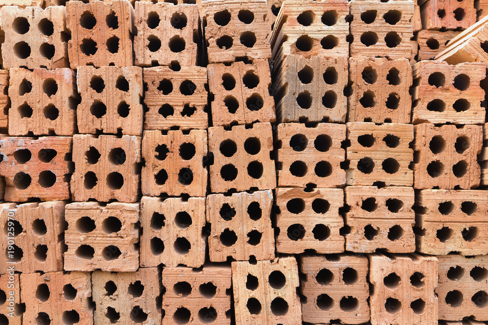 Stacks of hard orange-brown bricks block, a building construction material.
