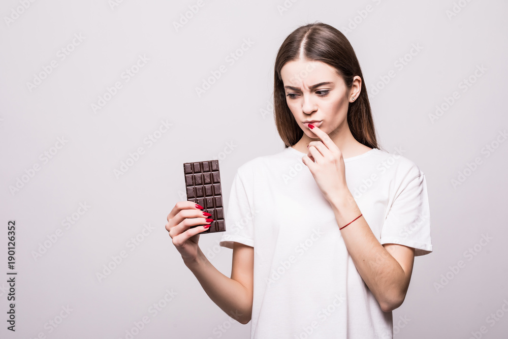 Portrait of a thoughtful pretty girl holding chocolate bar isolated over white background. Health concept. Portrait of a thoughtful pretty girl holding chocolate bar isolated over white background. Health concept.