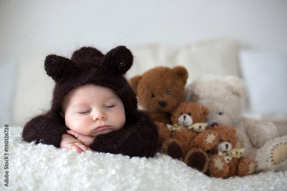 Sweet little baby boy, dressed in handmade knitted brown soft teddy bear overall, sleeping cozy - obrazy, fototapety, plakaty 