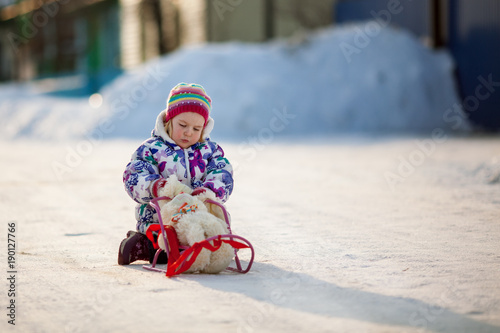 Winter Walk of small pretty ruddy girl, child plays with soft toy