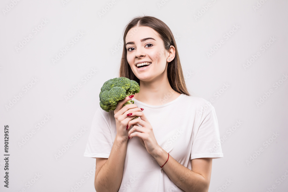 Portrait of a lovely pretty girl holding broccoli isolated over white background. Health concept Portrait of a lovely pretty girl holding broccoli isolated over white background. Health concept