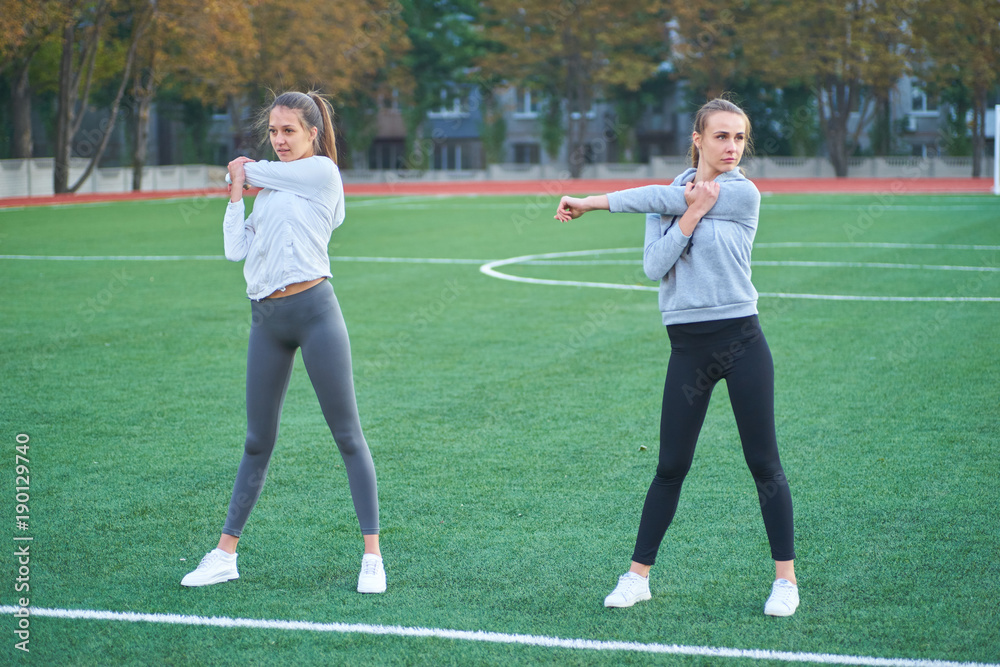 Two beautiful sports girls exercising together on a lawn Two beautiful sports girls exercising together on a lawn