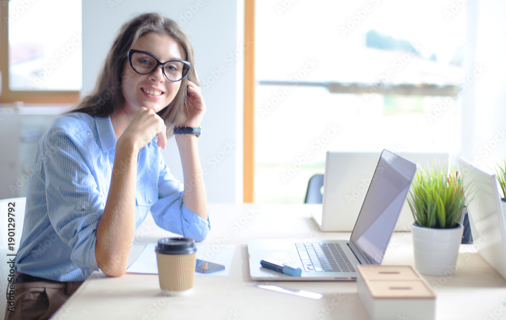Obraz premium Young woman sitting in office table, looking at laptop computer screen . Young woman