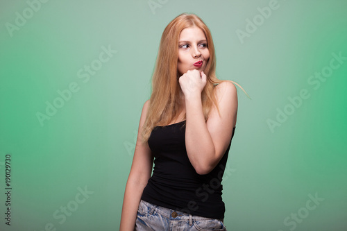 Blonde woman making a silly face on green background in studio © DC Studio