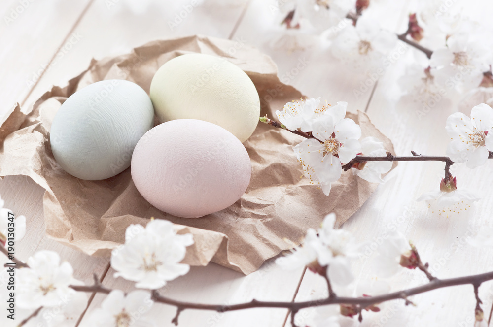 Colored eggs with flowers on a white wooden background. The concept of the holiday of Easter. Easter light background. Toned effect.
