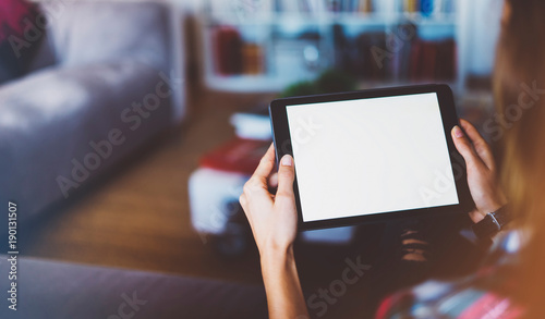 Hipster girl using tablet technology in home atmosphere, girl holding computer with blank screen on background, female hands texting on relax holiday, mockup templates gadget, blur lifestyle concept