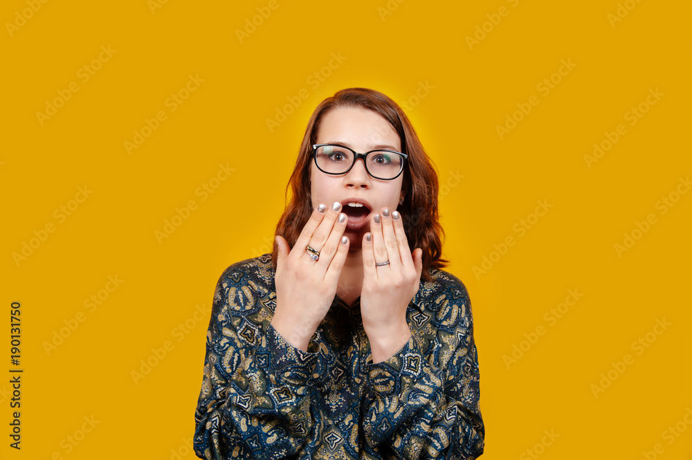 Portrait of a shocked casual girl wearing eye glasses and looking at the camera on orange background. Portrait of a shocked casual girl wearing eye glasses and looking at the camera on orange background.