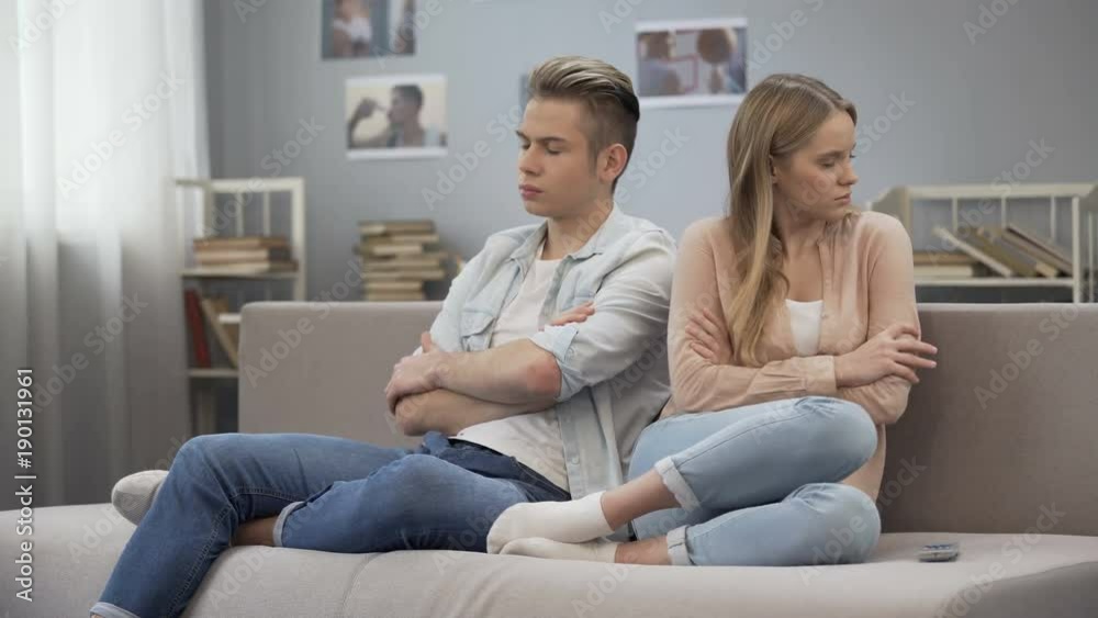 Two frustrated teenagers sitting on couch turn way, quarrel misunderstanding Two frustrated teenagers sitting on couch turn way, quarrel misunderstanding