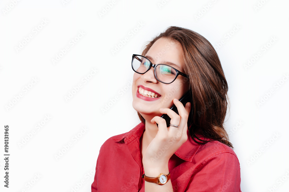Portrait of a smiling young woman talking on mobile phone while standing and looking away at copy space over white background Portrait of a smiling young woman talking on mobile phone while standing and looking away at copy space over white background