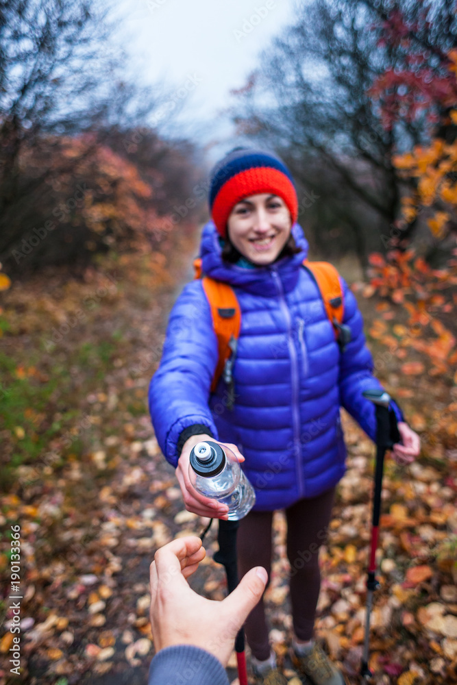 The girl is holding out a bottle of water.