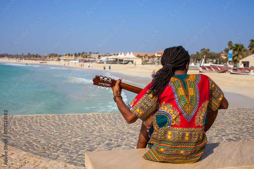Fototapeta premium Muzyk z gitarą i włosami rasta na plaży Santa Maria na Sal na Wyspach Zielonego Przylądka