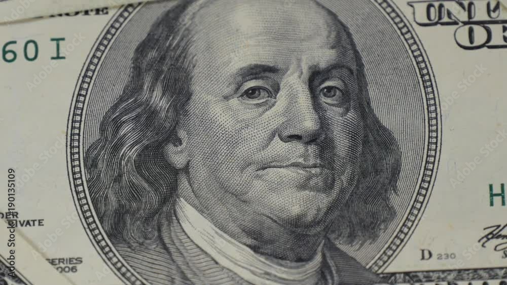 Hundred dollar bills. Portrait of Benjamin Franklin close-up. Macro photography of banknotes. The motion camera slider.
