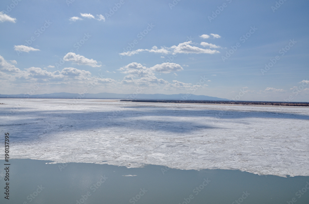 Fototapeta premium Kabelny and Big Ussuriysky islands and ice floes on Amur river on a sunny day in early spring Admiral Nevelsky embankment, Khabarovsk, Russia