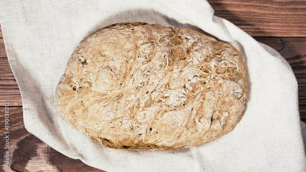 Man puts whole homemade bread on wooden table. Delicious homebaked bread on linen napkin. Man puts whole homemade bread on wooden table. Delicious homebaked bread on linen napkin.