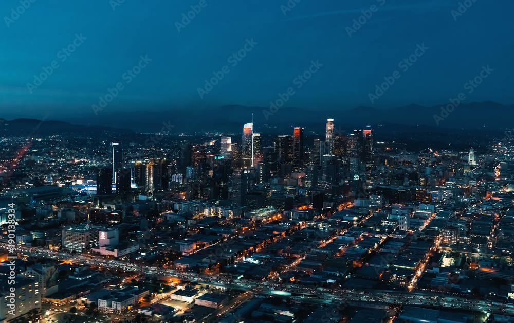 Fototapeta premium Widok z lotu ptaka centrum Los Angeles o zmierzchu z młodą kobietą, trzymając w ręku smartfon