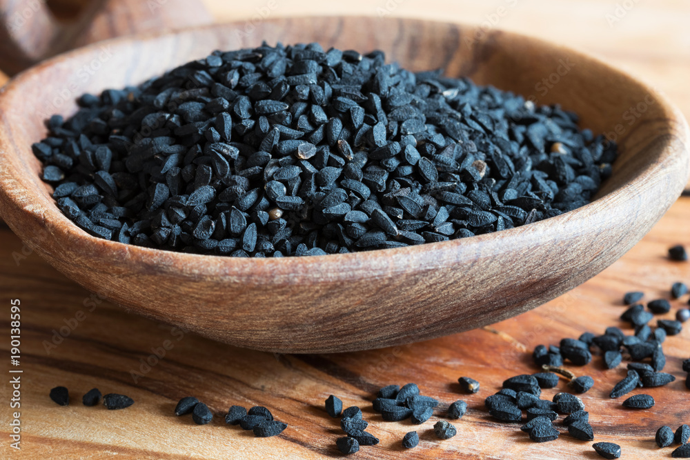 Black cumin seeds on a wooden spoon Black cumin seeds on a wooden spoon