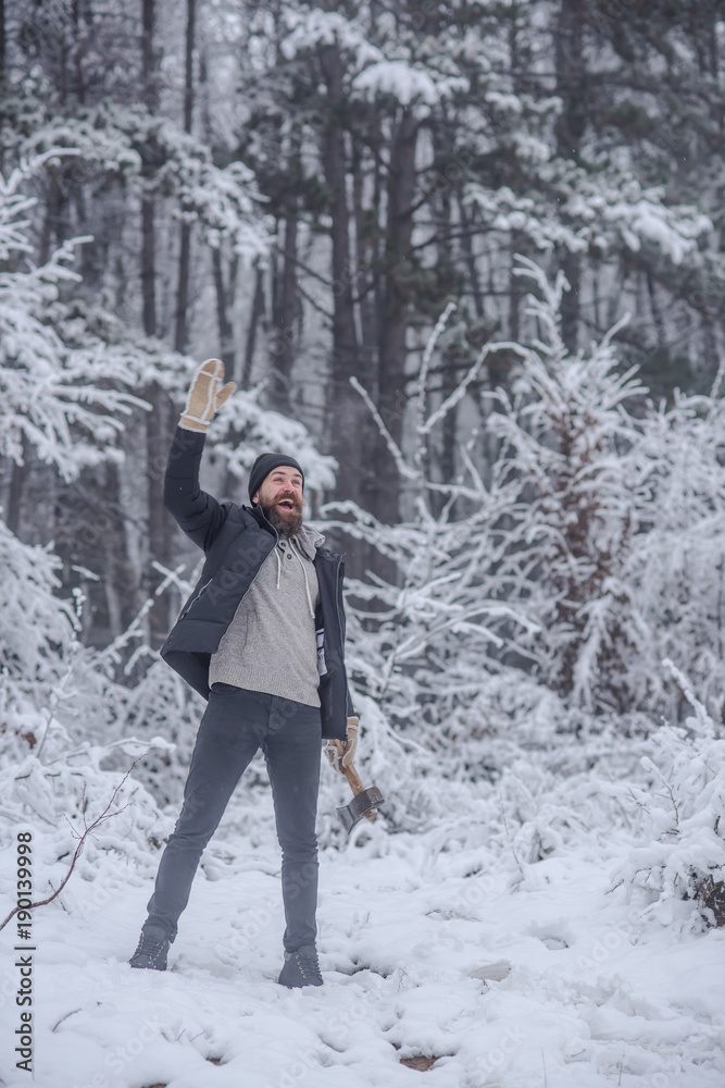Bearded man with axe in snowy forest.