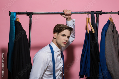 Man hold rack with jackets on hangers in wardrobe