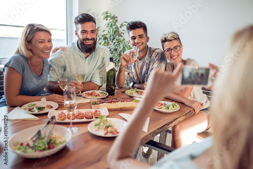 Portrait of happy friends taking selfie at lunch table.