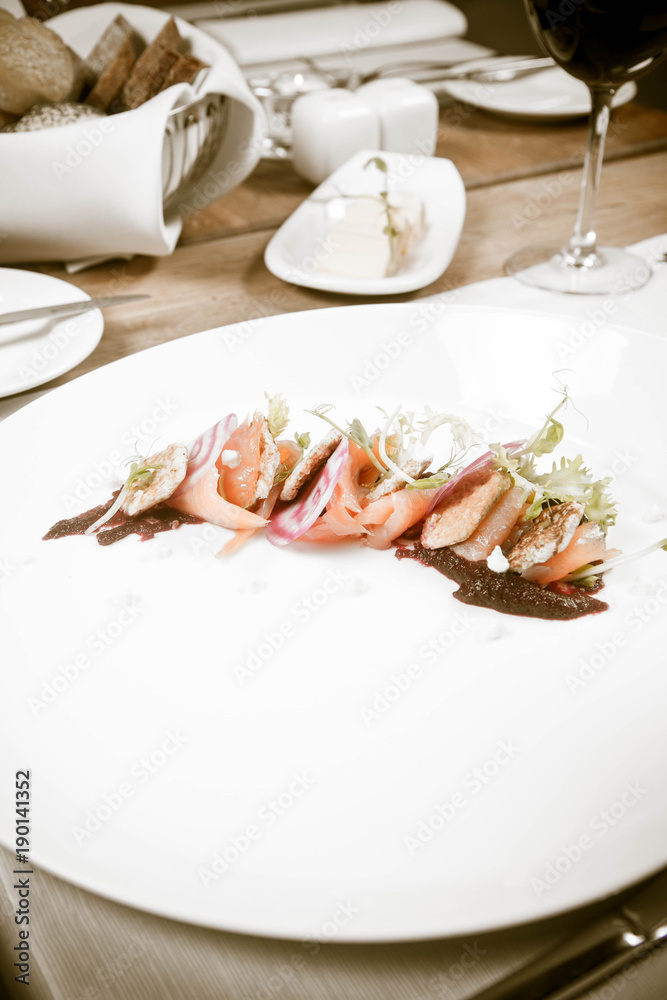 Smoked salmon with roasted beetroots sauce, russian pancakes and horseradish cream served in a restaurant Smoked salmon with roasted beetroots sauce, russian pancakes and horseradish cream served in a restaurant