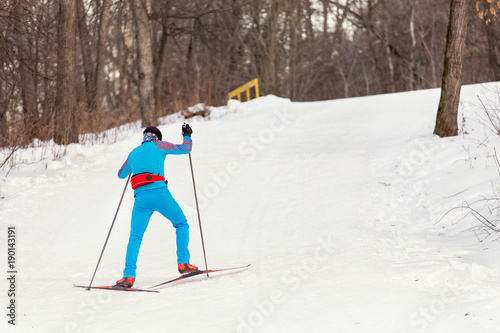 Man wearing sports uniform on cross-country skiing in a city park, healthy lifestyle concept