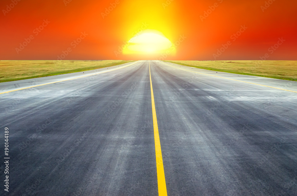 Naklejka premium Runway at the airport the horizon at sunset in the center of the sun.
