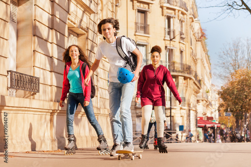 Canvas Print Boy skateboarding and girls rollerblading at city