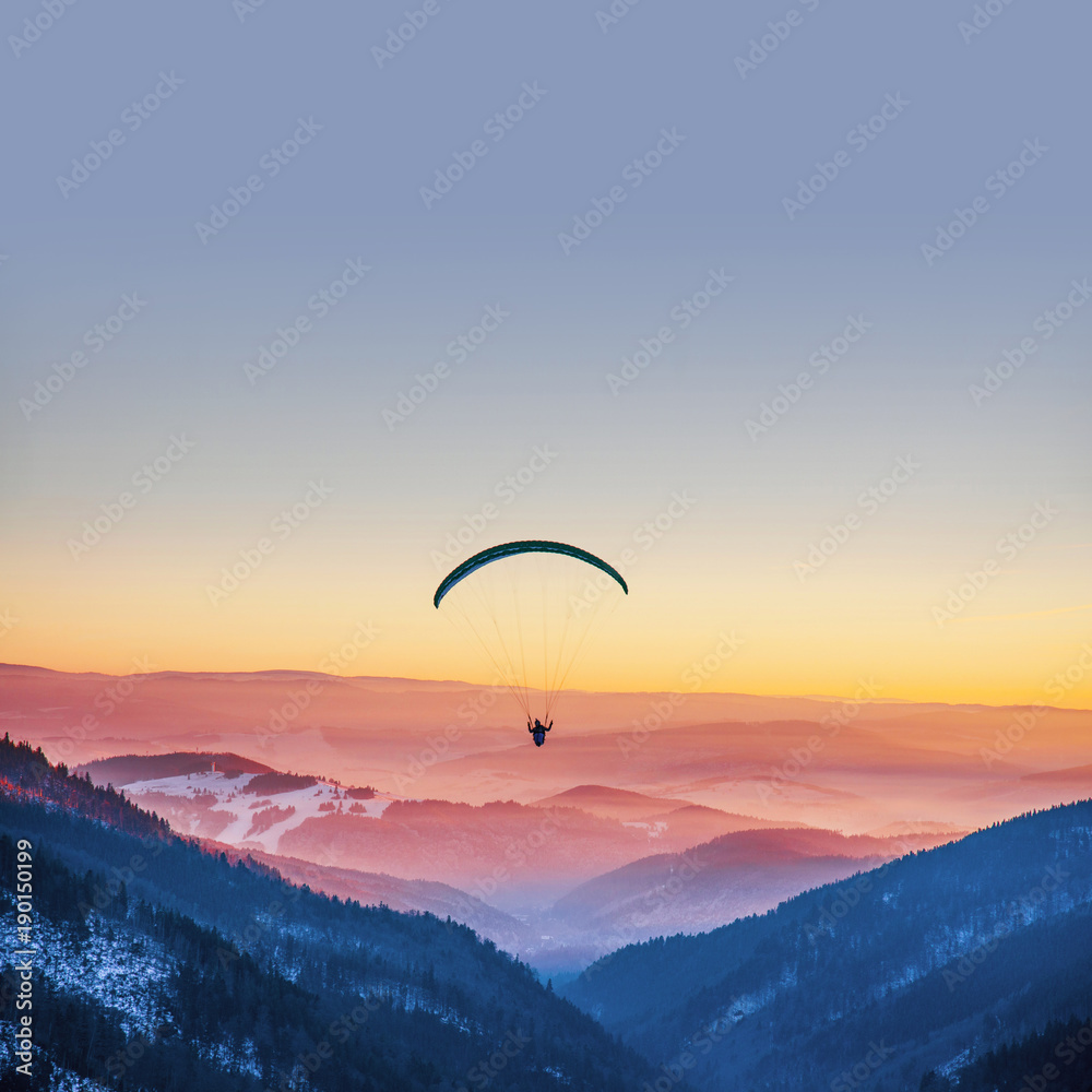 Parachuting in sunset light above mountains