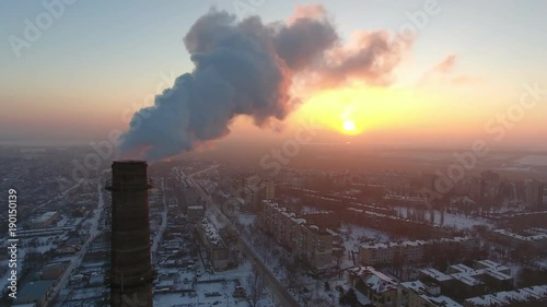 A wonderful bird`s eye view of a sky-high brick tube with a stream of heavy smoke at a splendid sunset. It sticks out impressively   photo