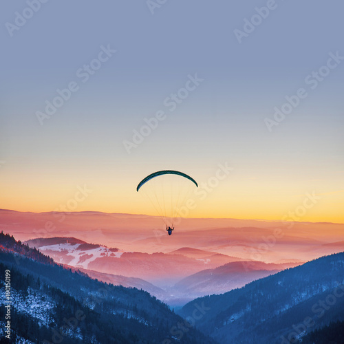 Parachuting in sunset light above mountains