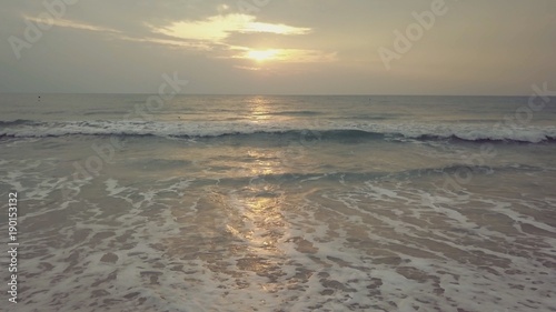 Sunset on the beach - Tranquil idyllic scene of a golden sunset over the sea, waves slowly splashing on the sand. Video. Waves crashing gently on quiet sandy beach