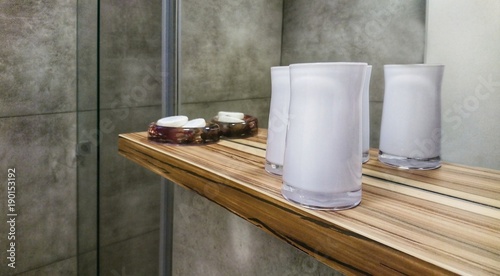 Bathroom wooden shelf with decorative candela glasses and soaps.