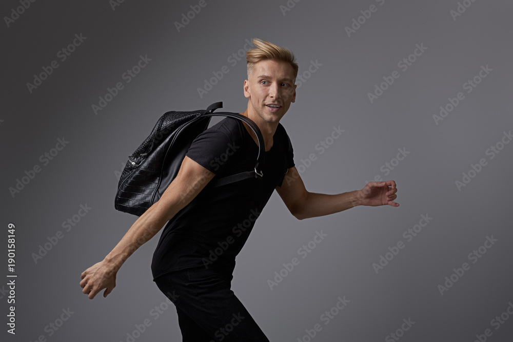 Handsome young man running with a backpack on shoulders Handsome young man running with a backpack on shoulders