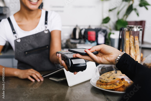 Customer making wireless payment using smartphone in cafe photo