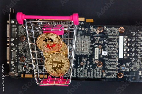 Stack of coins bitcoin in mini shopping cart toy on the video card, concept of mining. Electronic virtual money for web banking and international network payment. Symbol of crypto currency photo