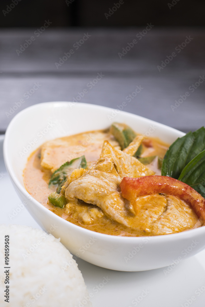 Thai red curry with chicken in white bowl served with rice