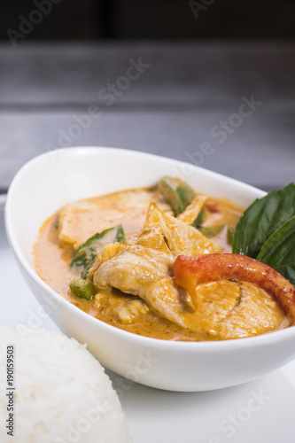 Thai red curry with chicken in white bowl served with rice