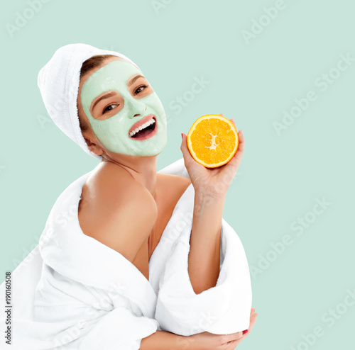 Beautiful woman with clay mask on pastel green background. Beauty and spa
