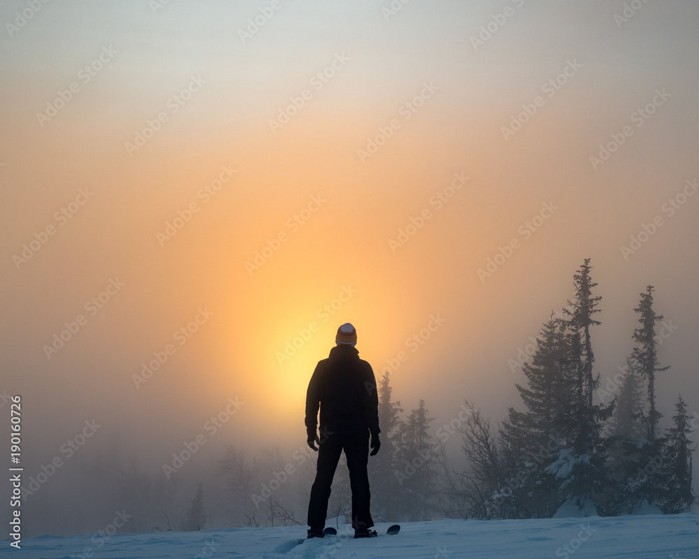 Man standing on top of mountain among golden glow sunset Man standing on top of mountain among golden glow sunset