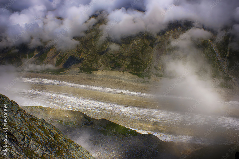 View on sunlit glacier through the clouds from a great height.