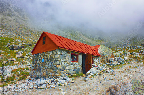 High mountains cottage for tourist and climbers rest on cloudy background.