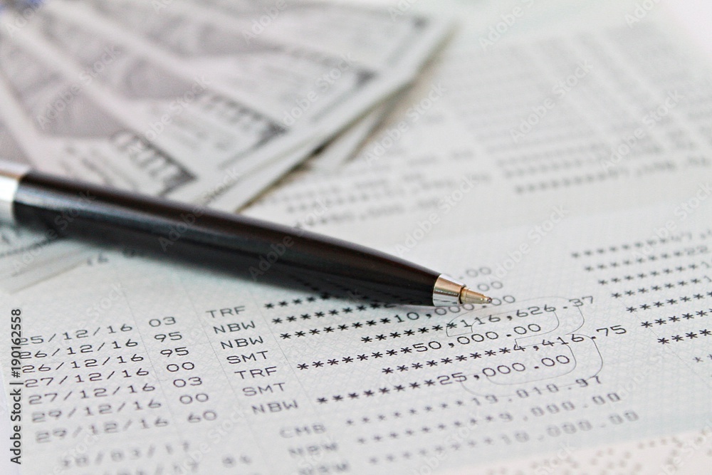 Business, finance, investment, accounting or money exchange concept : American Dollars cash money on savings account passbook or financial statement Business, finance, investment, accounting or money exchange concept : American Dollars cash money on savings account passbook or financial statement