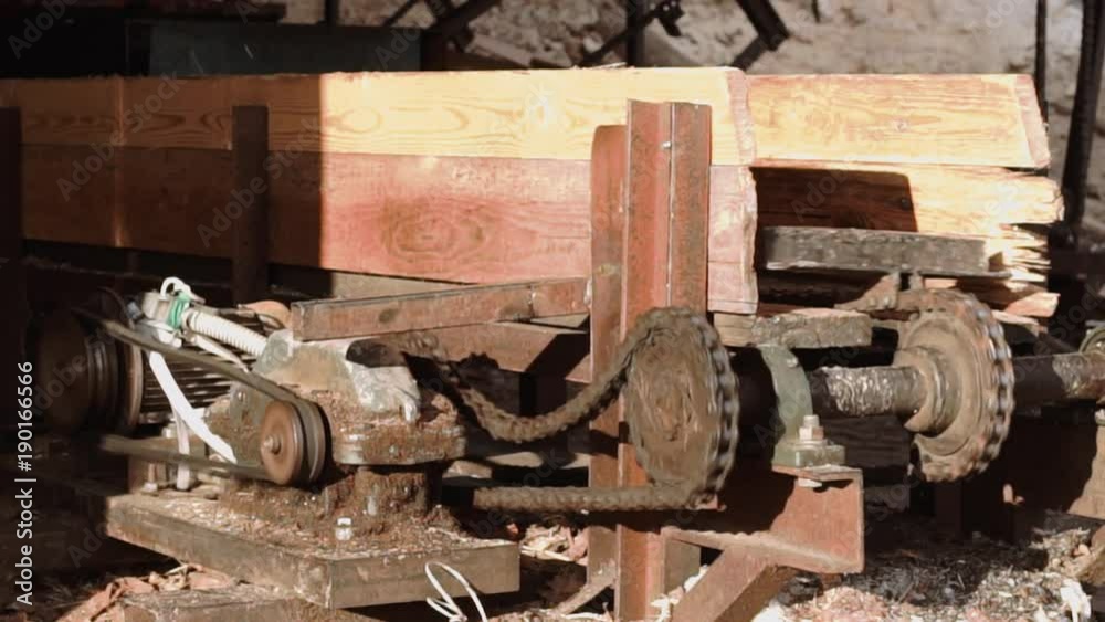 Old handmade conveyor carrying wood planks at sawmill. Lots of sawdust, sunny day, slow motion Old handmade conveyor carrying wood planks at sawmill. Lots of sawdust, sunny day, slow motion