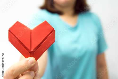 An asian woman holding heart origami in front of her chest. A woman giving red heart paper to someone. Love and give concept for valentine day.