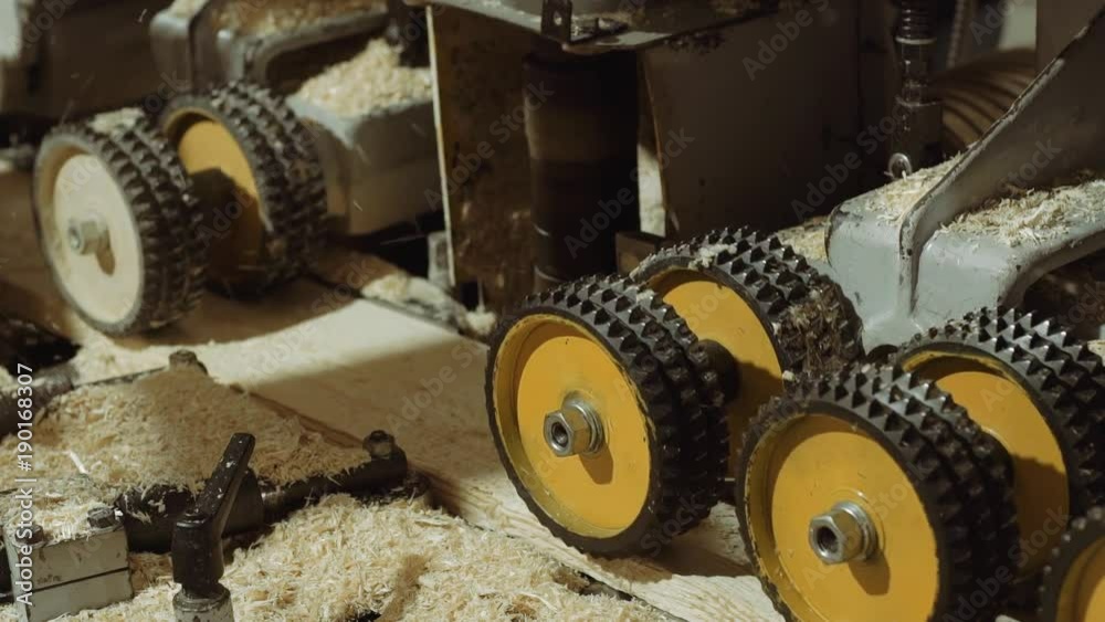 Rolling spiked wheels of board refiner machine working on wood at sawmill production, close up