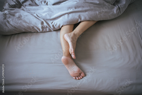 Barefoot and leg under blanket on the bed