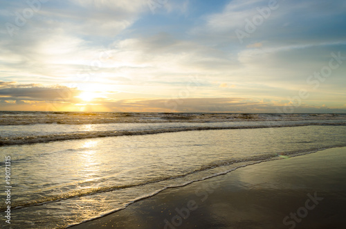 view of sunrise on a beach with the reflection of the sun in the sea water.