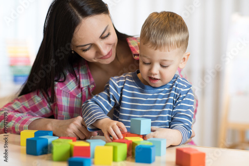 Child boy together with mother playing toys