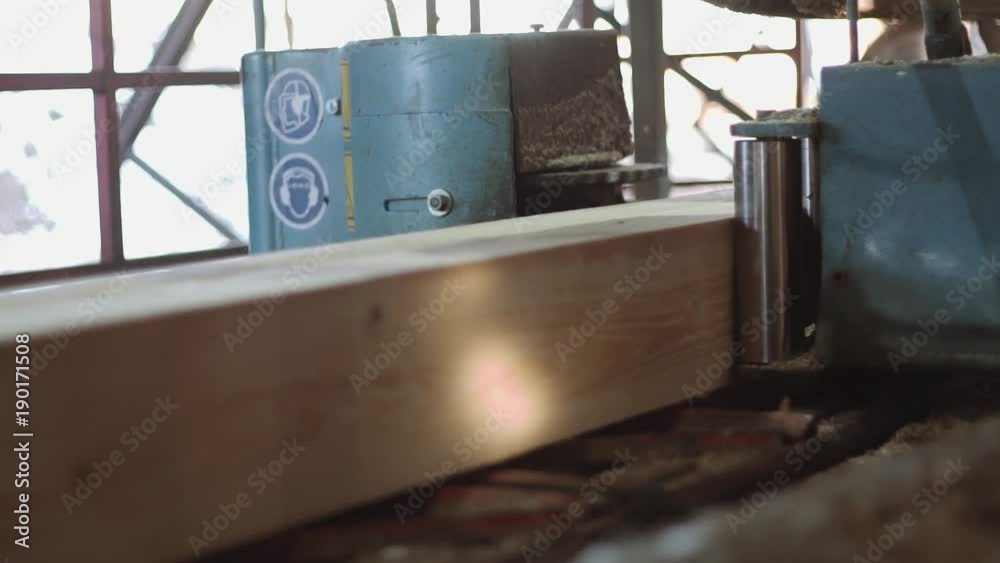 Lumber block cutting on metal circular saw in machine at woodwork factory, lots of sawdust, sunny day outside Lumber block cutting on metal circular saw in machine at woodwork factory, lots of sawdust, sunny day outside