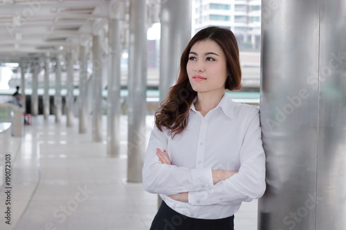 Confident young Asian busineswoman leaning a pole at walkway outside office. Leader business woman concept.